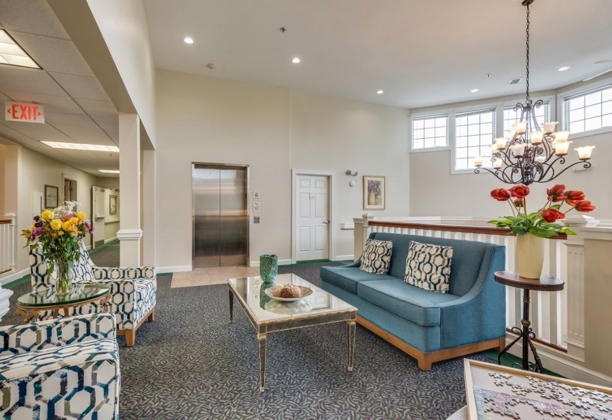 A modern lobby with comfortable seating and stylish decor, featuring an elevator and carpeted floor.