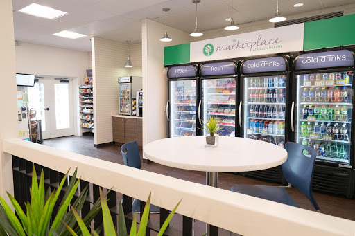 A modern cafe interior featuring a seating area and refrigerators stocked with various snacks and beverages.