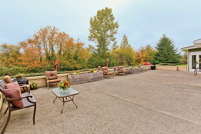 A spacious outdoor patio with furniture set against an autumn landscape of colorful trees.