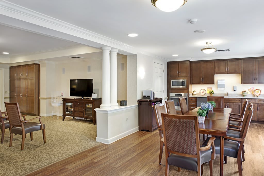 A modern open-concept living and dining area with a connected kitchen, featuring wood flooring and elegant furniture.