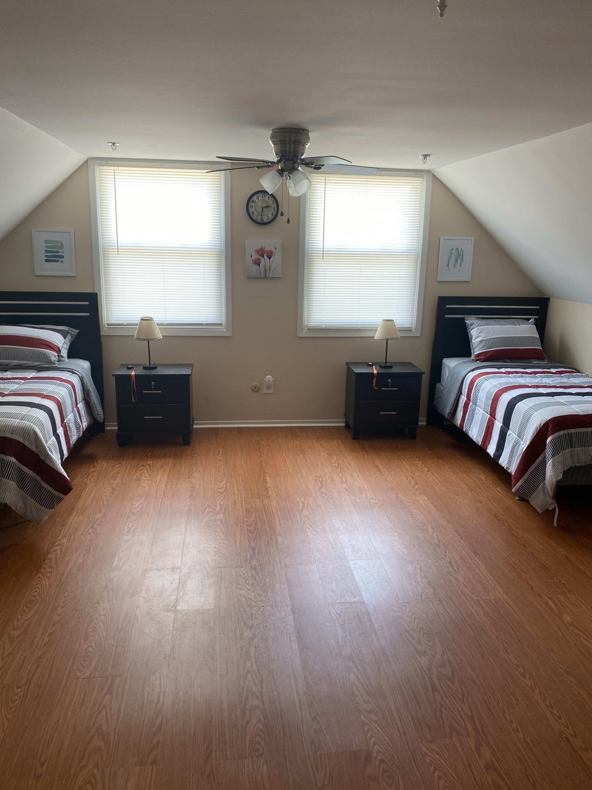 A minimalist attic bedroom with twin beds and wooden flooring.