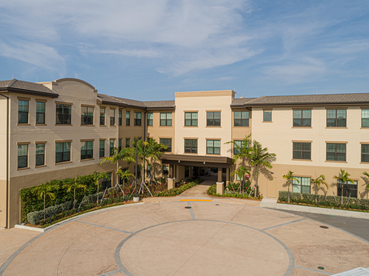 A three-story building with a welcoming entrance surrounded by landscaping.