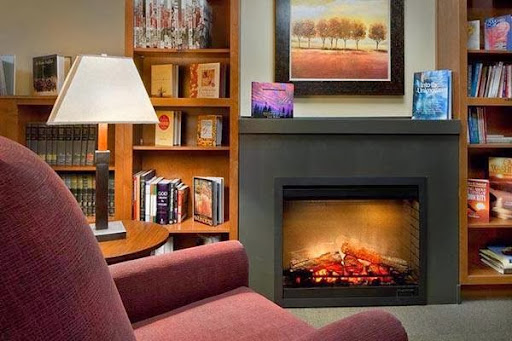 A cozy living room featuring a warm fireplace, a bookshelf filled with books, and a comfortable armchair.