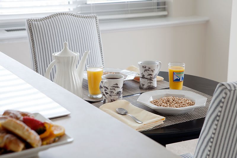 A cozy breakfast setup with coffee, cereal, and orange juice on a neatly set table.