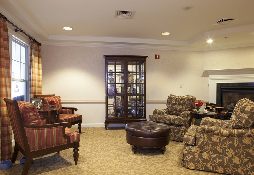 A cozy living room with comfortable armchairs, a wooden cabinet, and a carpeted floor.