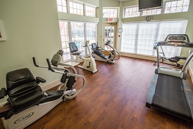 A small gym room featuring various cardio exercise machines including stationary bikes and a treadmill.