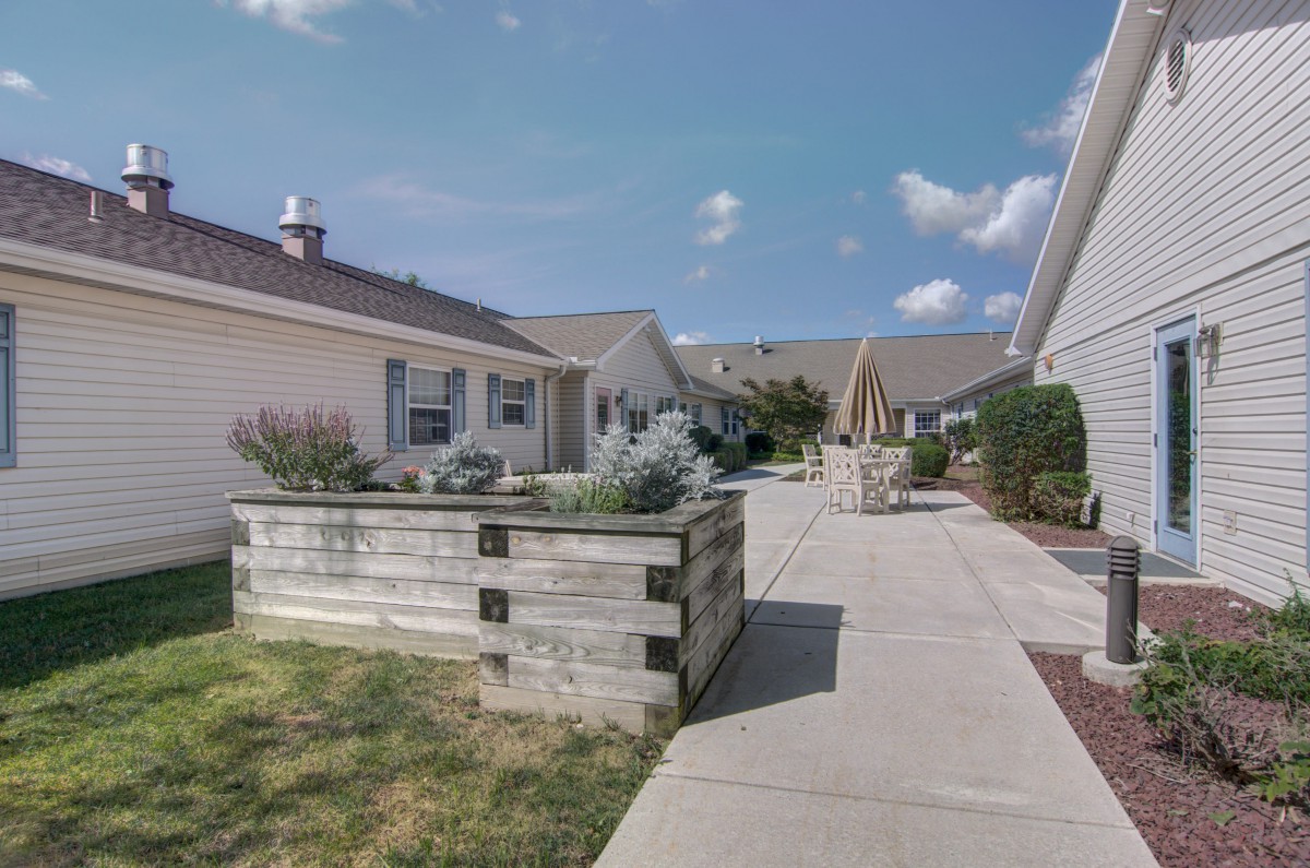 A peaceful suburban neighborhood with well-maintained houses and a paved walkway.