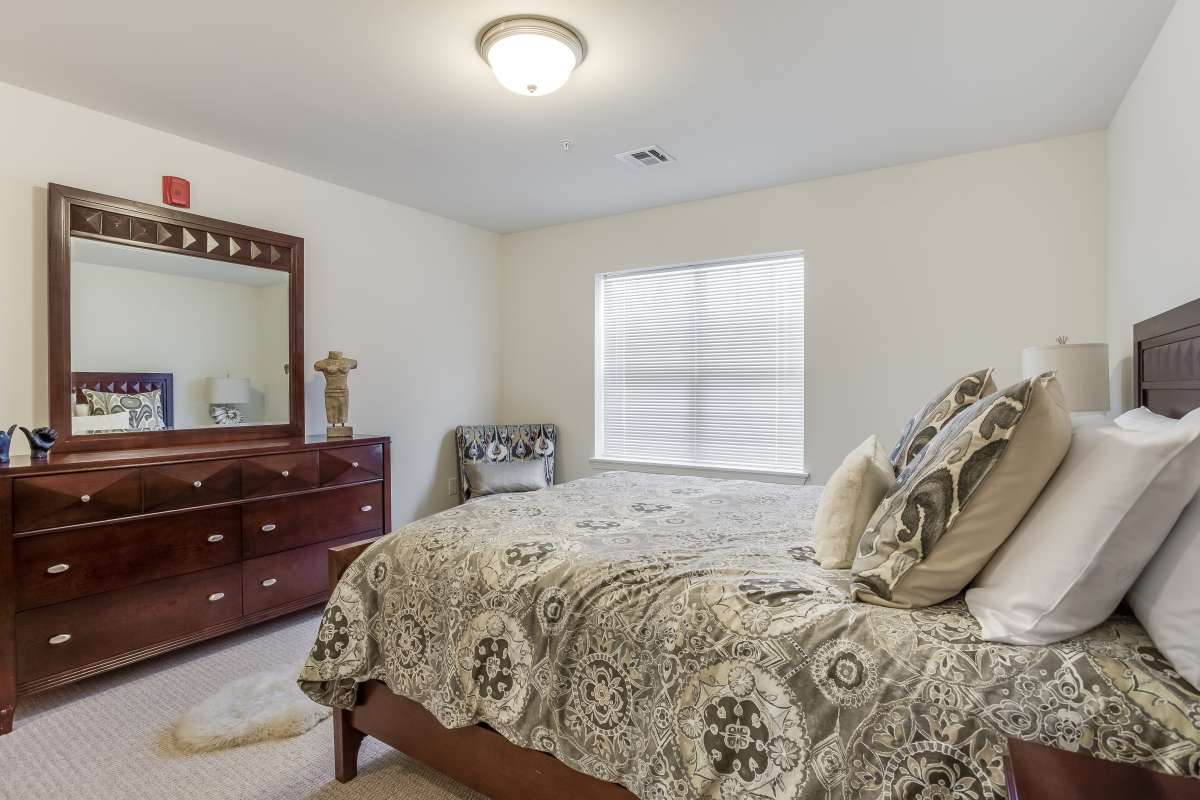A cozy bedroom with a patterned bedspread and wooden furniture.