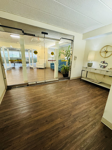 A spacious and inviting lobby featuring modern decor, elegant wooden flooring, and natural light filtering through glass doors.