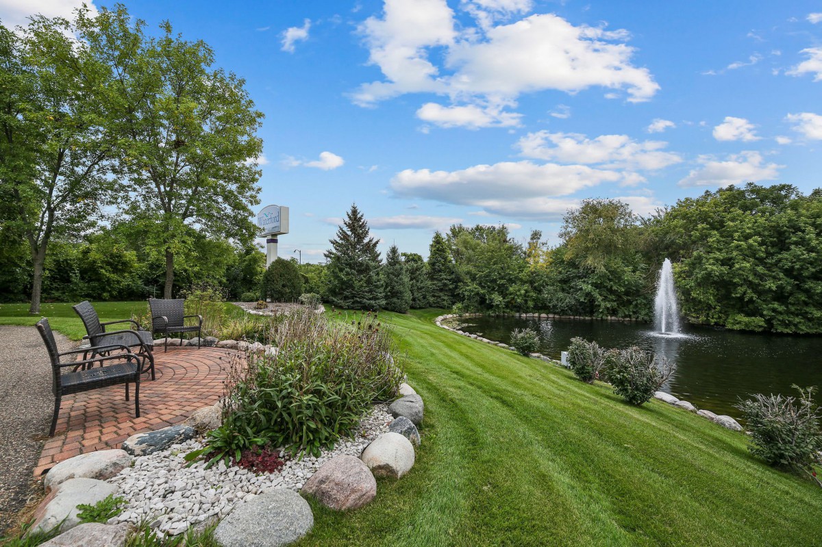 A tranquil garden with a well-manicured lawn, a pathway, and a pond with a fountain.