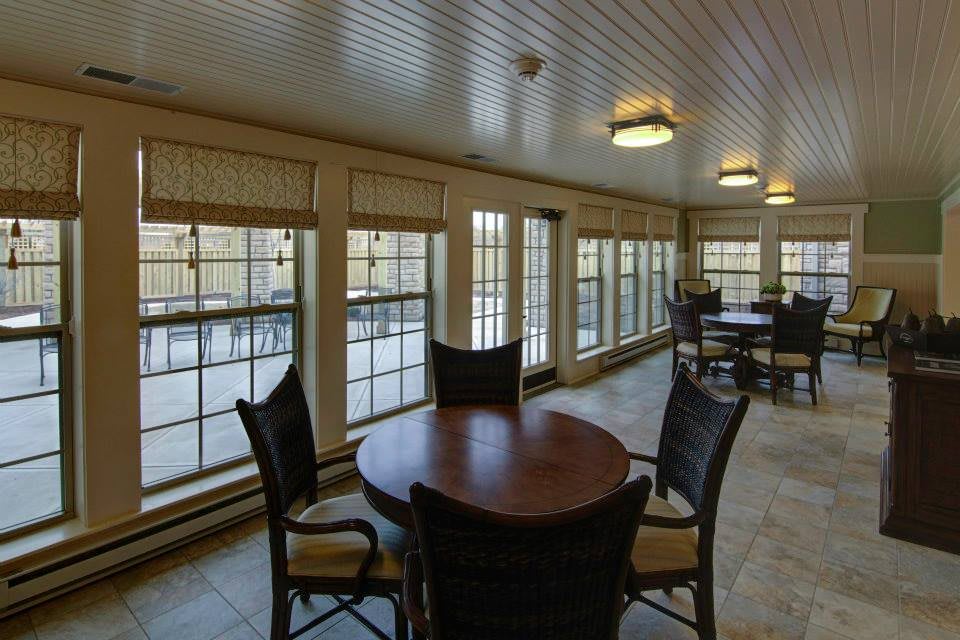 A well-lit dining area with multiple tables and chairs arranged by large windows.