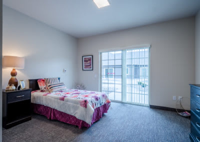 A modern, minimalist bedroom with a single bed and large window.