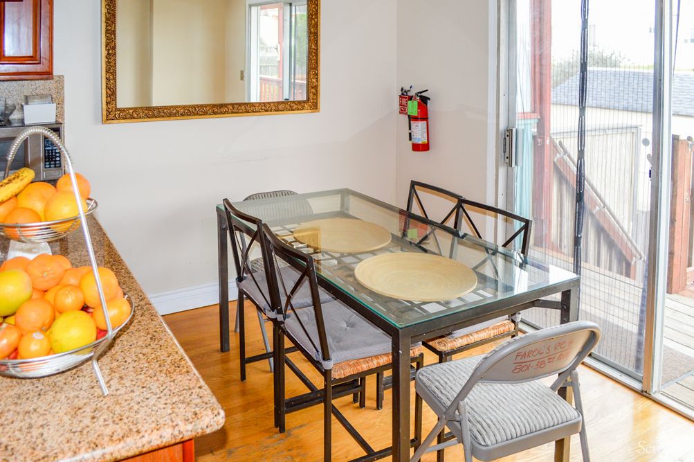 A dining room with a glass table, chairs, and a large mirror on the wall.