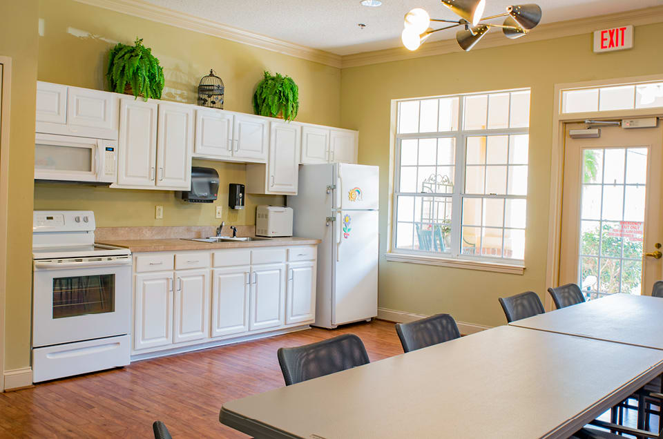 A bright kitchen and dining area with white cabinets, a refrigerator, and a large window.