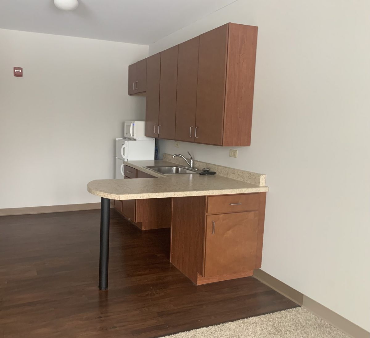 A compact apartment kitchen with wooden cabinets and a small countertop.