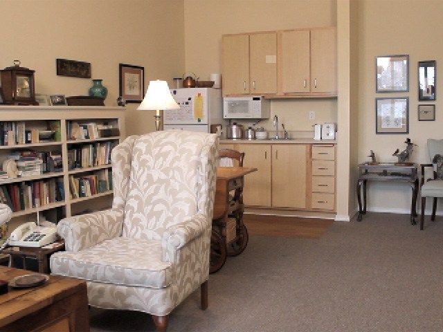 A cozy living room with an armchair and a small kitchen area.