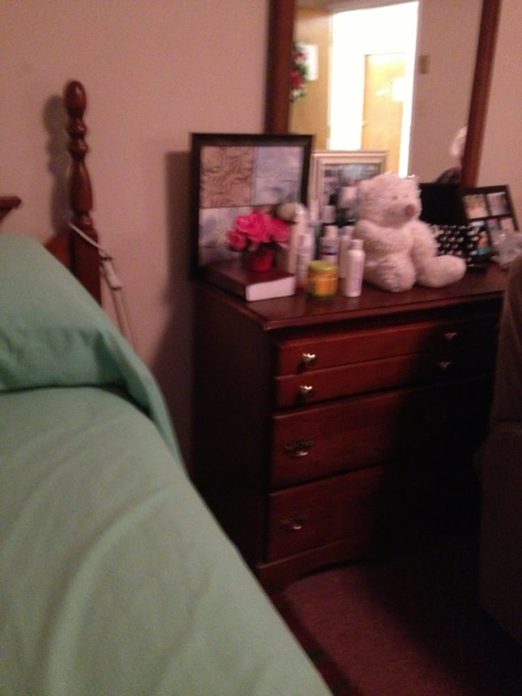 A cozy bedroom scene with a dresser topped with personal items and a teddy bear.