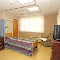 A hospital room with a bed, television, and comfortable chair.