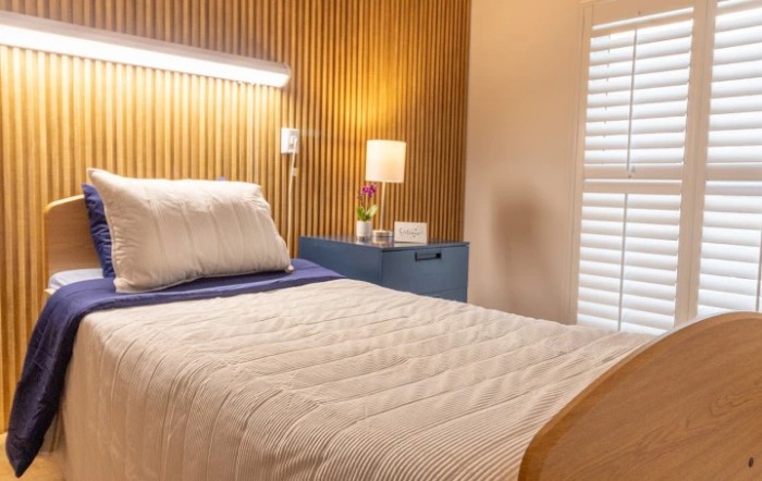 A modern bedroom with a wooden headboard, cozy lighting, and a neatly made bed.