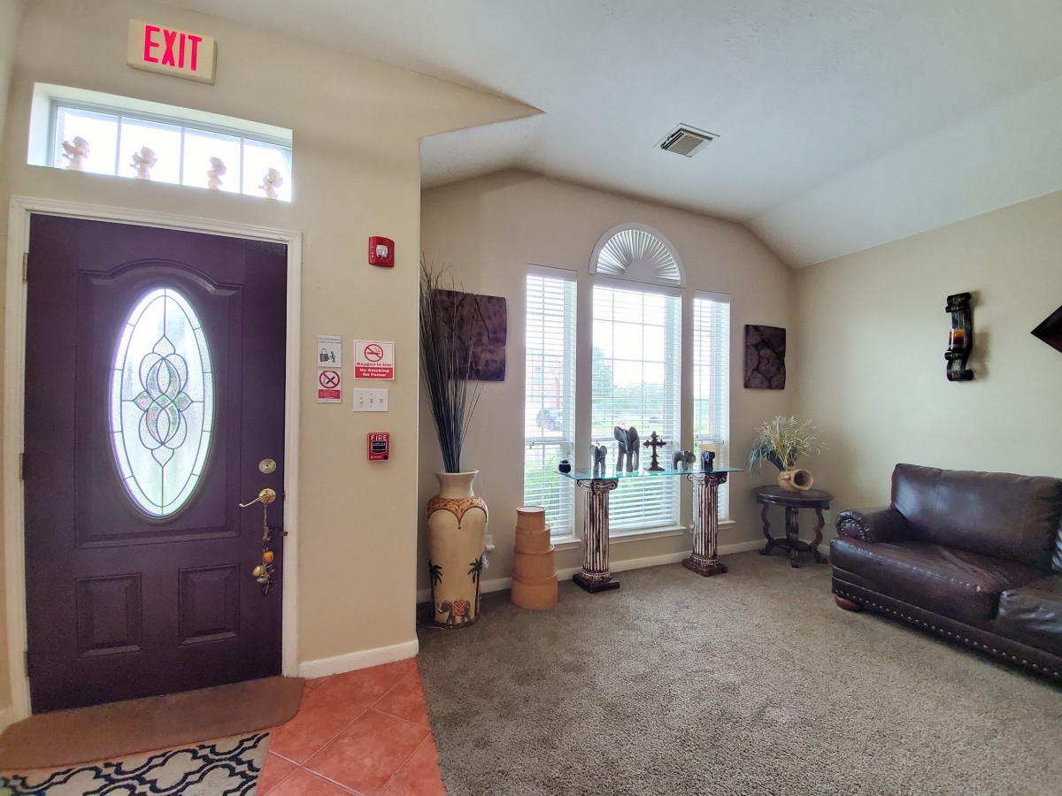 A cozy entryway and living area featuring a sofa, large windows, and decorative elements.