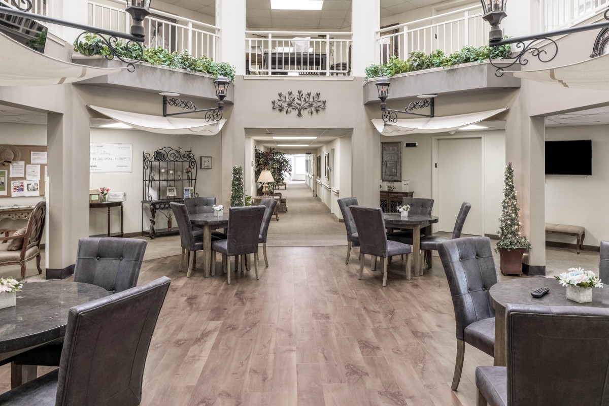 A spacious indoor atrium with tables and chairs arranged in a well-lit area, decorated with plants and elegant decor.