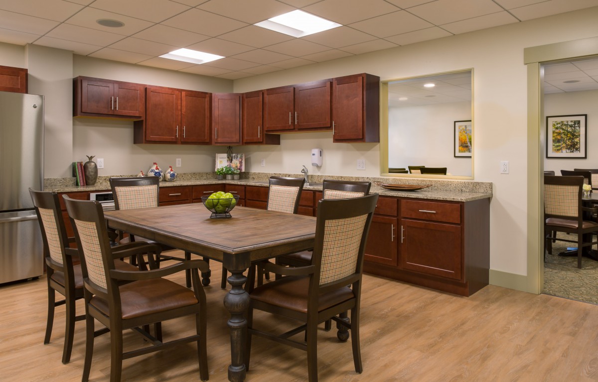 A modern kitchen with wood cabinets and a dining table equipped with chairs.
