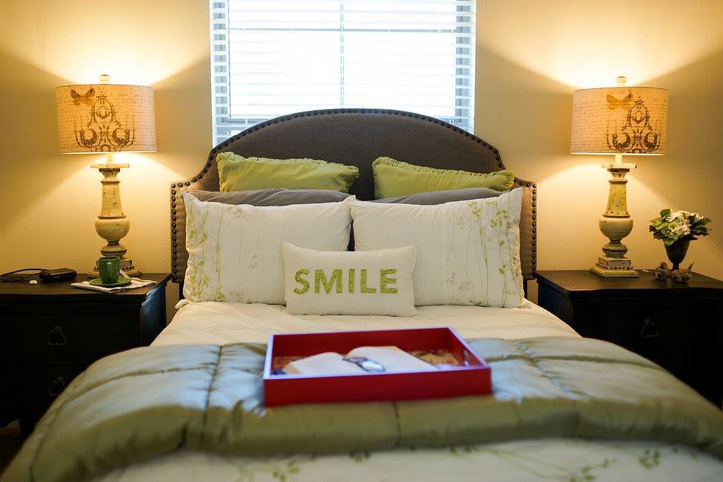 A cozy bedroom with a neatly made bed, featuring decorative pillows and bedside lamps.