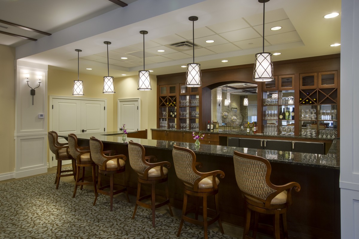 An elegantly designed bar area with high-backed chairs and pendant lighting.