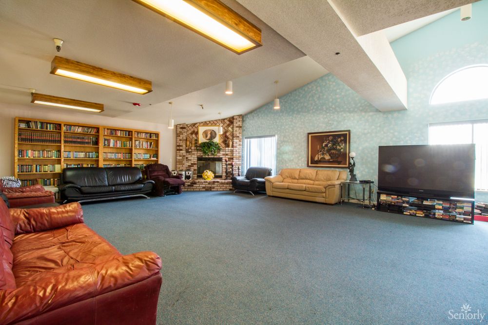 Spacious living room with multiple couches, bookshelves, and large windows.
