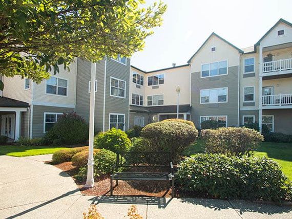 A residential building surrounded by neatly maintained gardens and bushes.