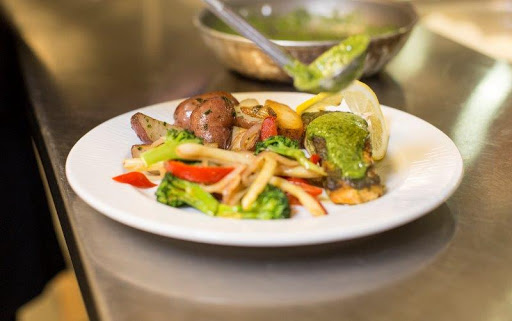 A vibrant plate of sauted vegetables and protein, garnished with fresh herbs and a slice of lime.