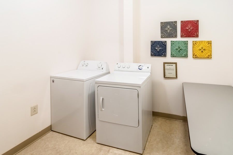 A laundry room featuring a washing machine and dryer with artwork on the wall.