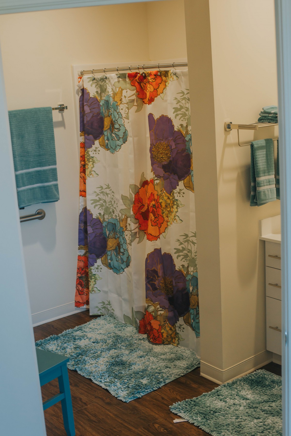 A bathroom with a colorful floral shower curtain and matching towels.