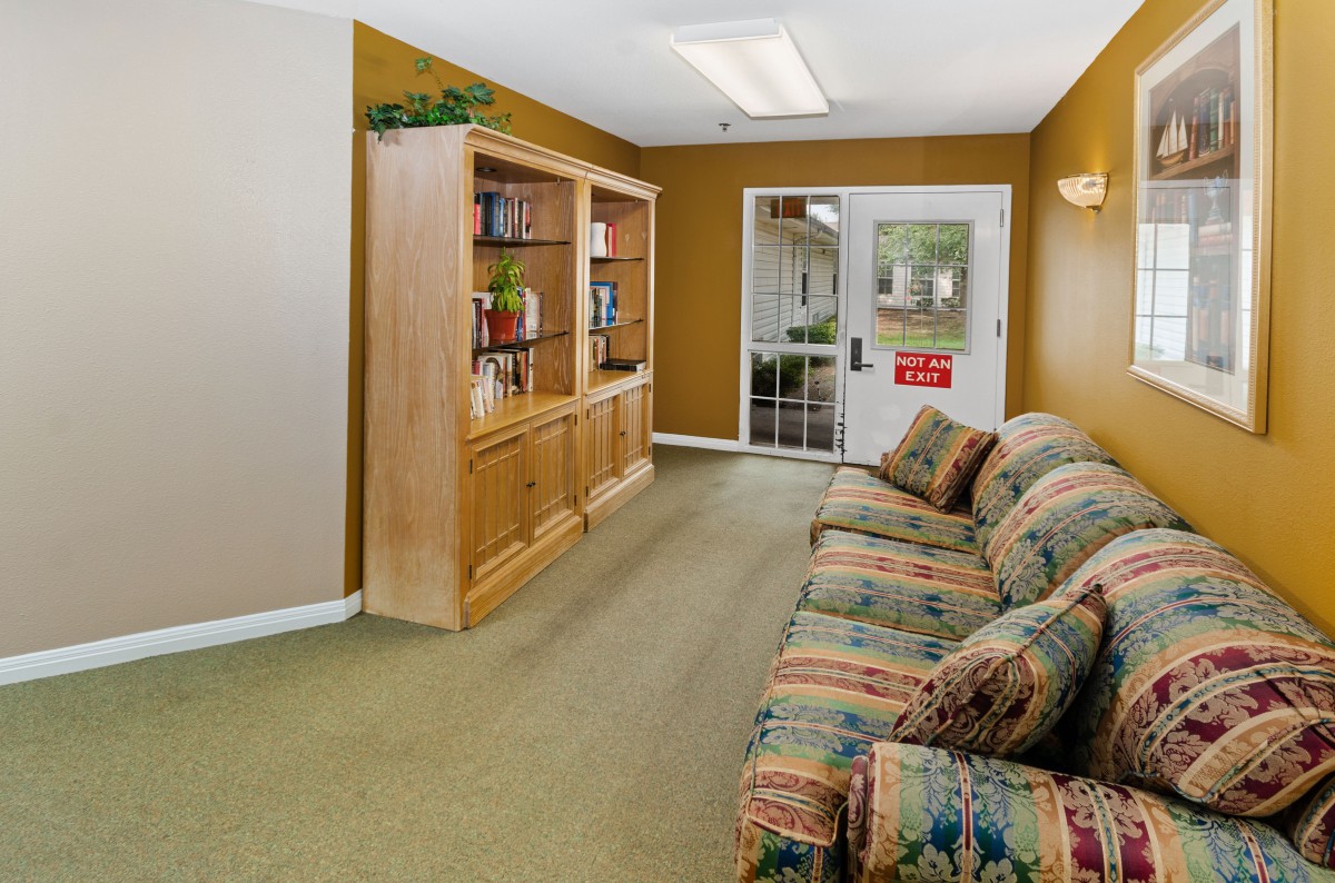 A comfortable living area featuring a patterned couch and a wooden shelving unit.