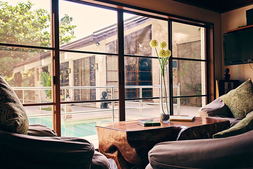 A spacious living room with large windows offering a serene outdoor view and abundant natural light.