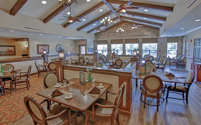 A spacious restaurant dining area with elegant wooden furniture and ceiling decorations.
