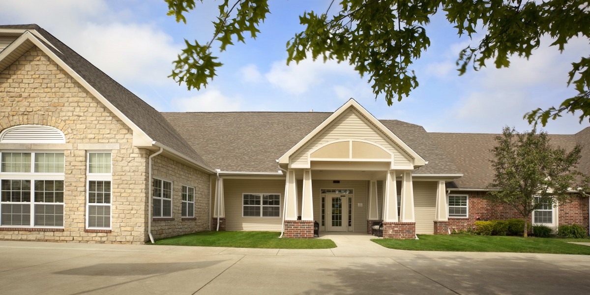 A residential building with a driveway and tree-covered entrance.