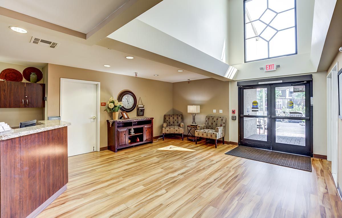 A welcoming lobby area with chairs, a lamp, and wood flooring.