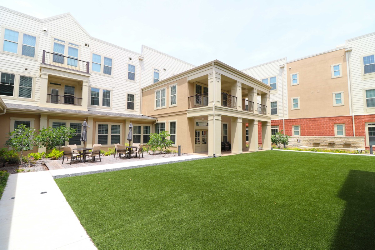 A modern apartment complex with a well-maintained lawn and outdoor seating.