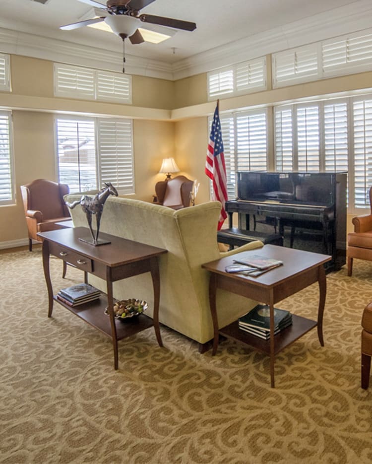 A well-furnished office space with a sofa, desk, and American flag.