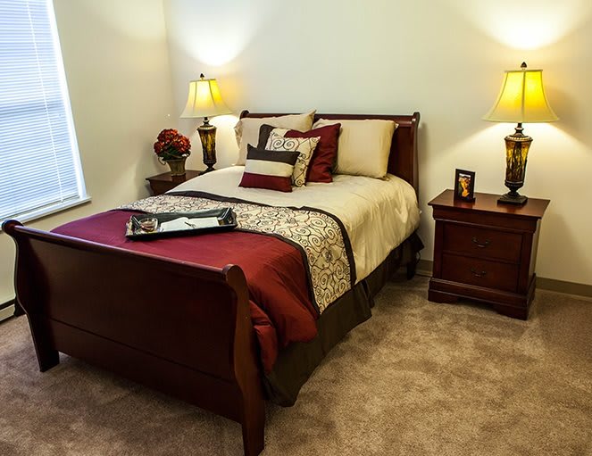 A cozy bedroom with a neatly made bed, decorative pillows, bedside tables, and ambient lighting.