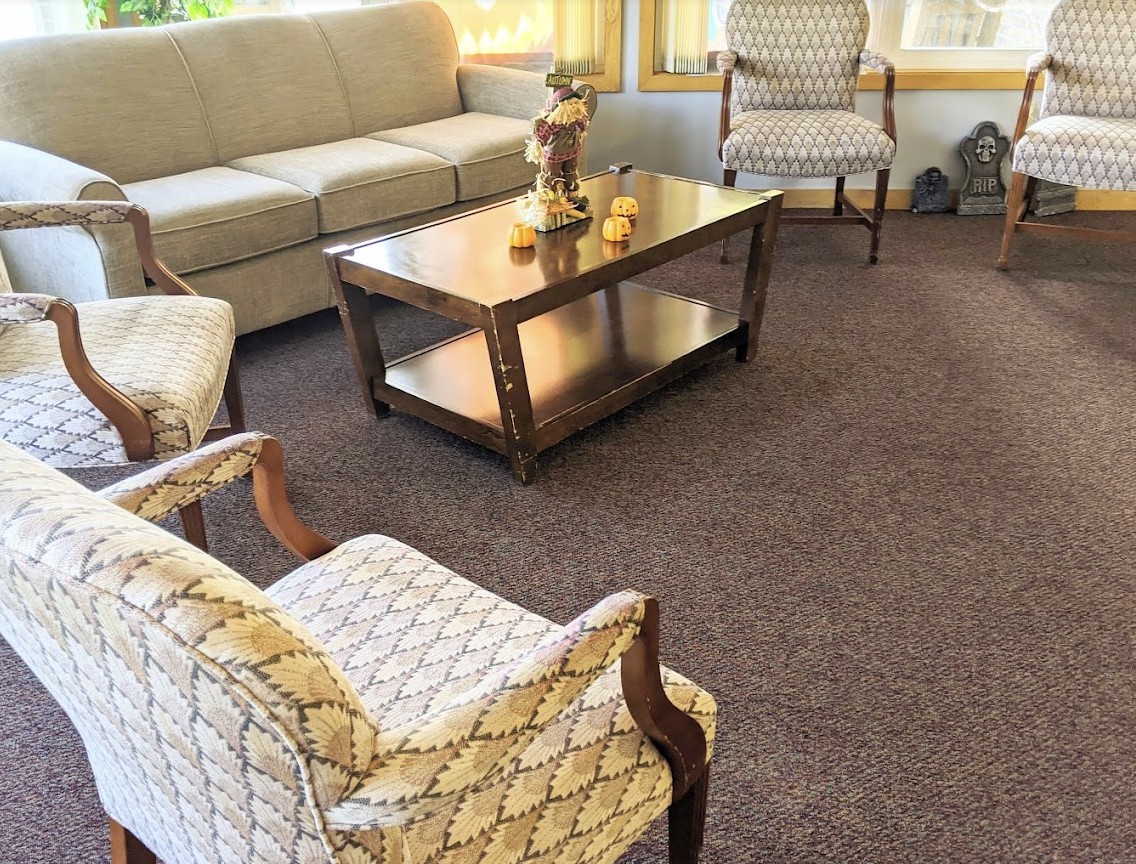 A cozy living room with a sofa, chairs, and a wooden coffee table on a carpet.