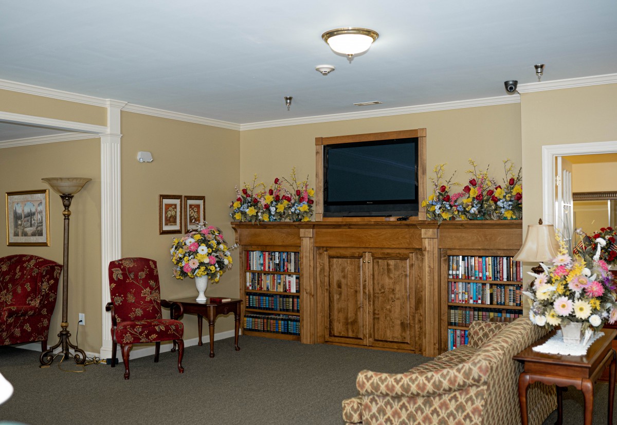 Cozy living room with a mounted television, bookshelves, and floral decor.
