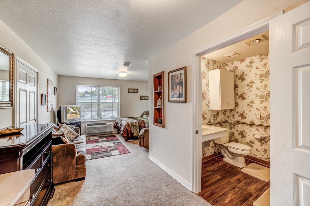 A cozy living room with adjacent bathroom featuring floral wallpaper.