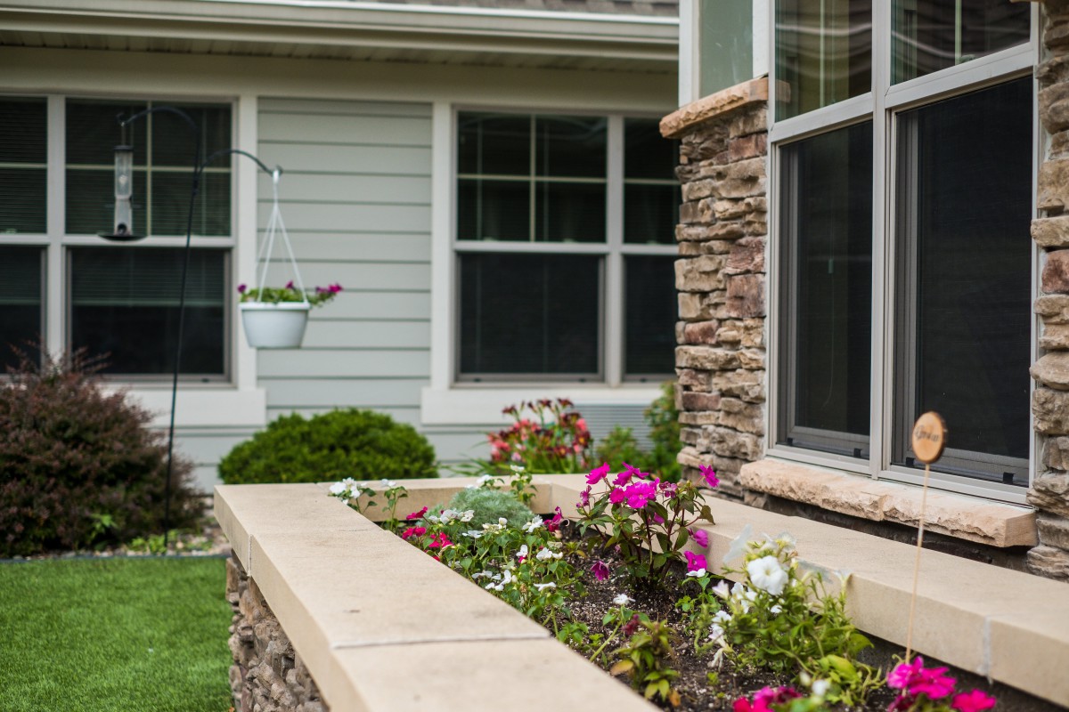 A beautifully landscaped garden with colorful flowers in front of a house with a stone facade.