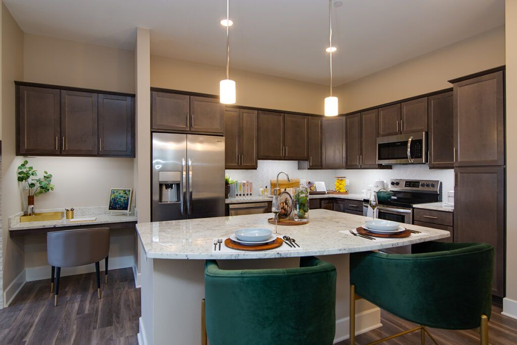 A modern kitchen featuring an island with bar stools, stainless steel appliances, and pendant lighting.