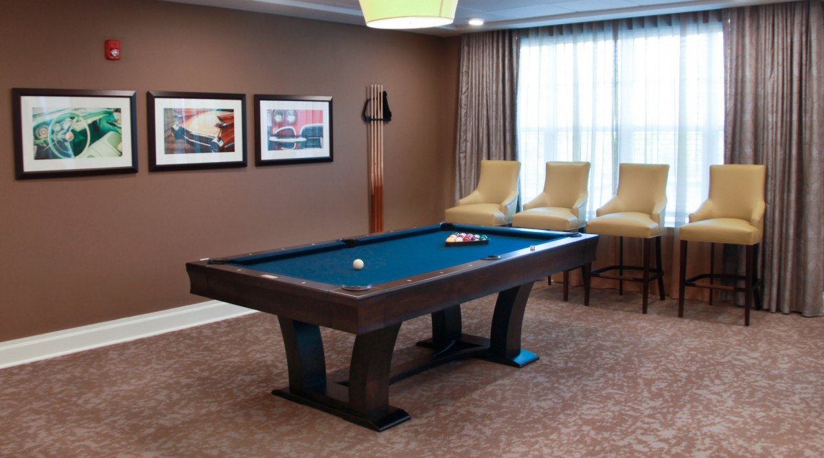 A well-furnished game room featuring a pool table, chairs, and artwork on the walls.
