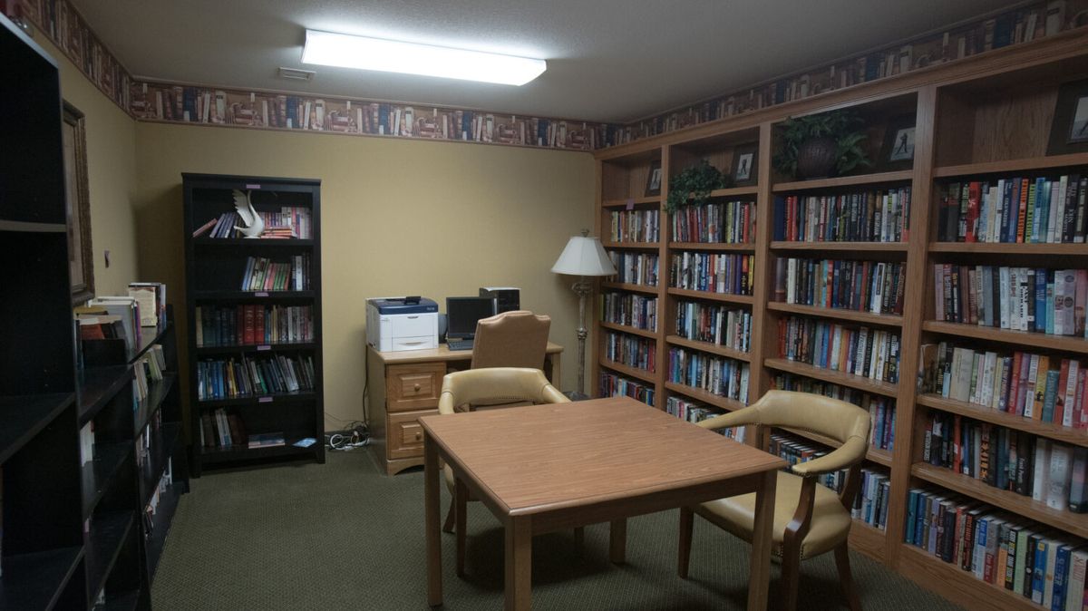 A quiet library room with bookshelves, a desk, and chairs.