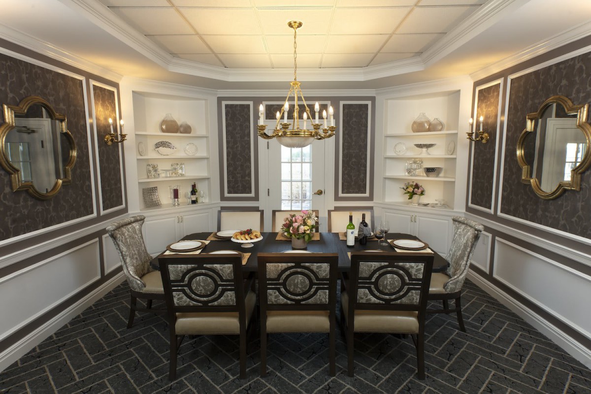 An elegantly decorated dining room featuring a chandelier and a well-set table.
