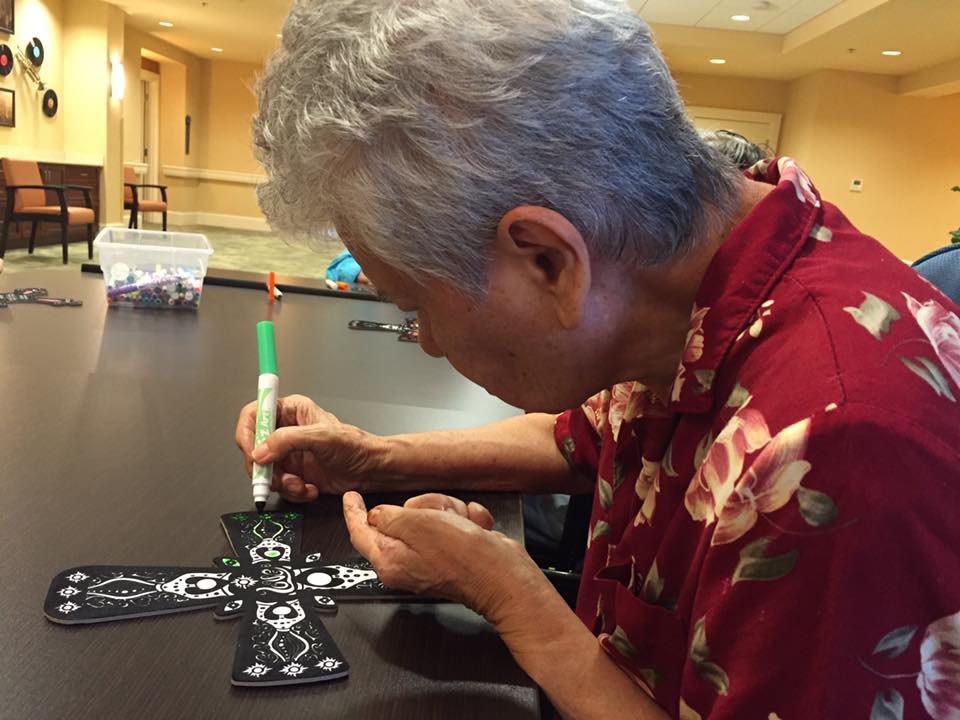 A person decorating a cross with intricate designs using a marker.